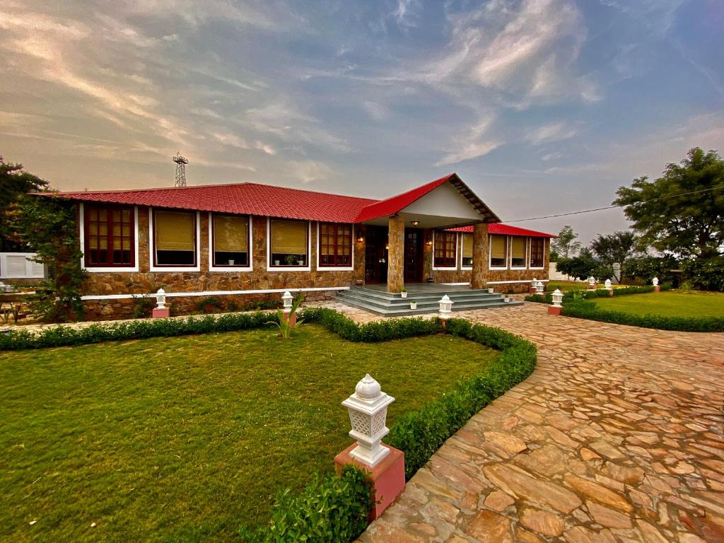 a house with a red roof and a grass yard at Sariska Safari Lodge in Thāna Ghāzi