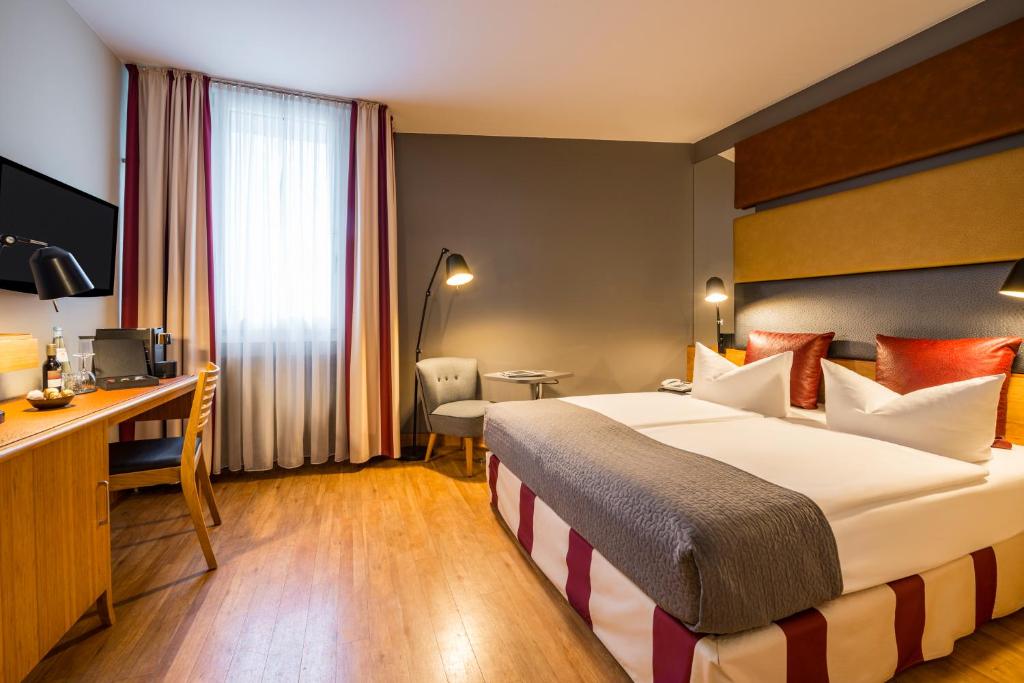 ベルリンにあるMercure Hotel Berlin Zentrum Superiorの大きなベッドとデスクが備わるホテルルームです。