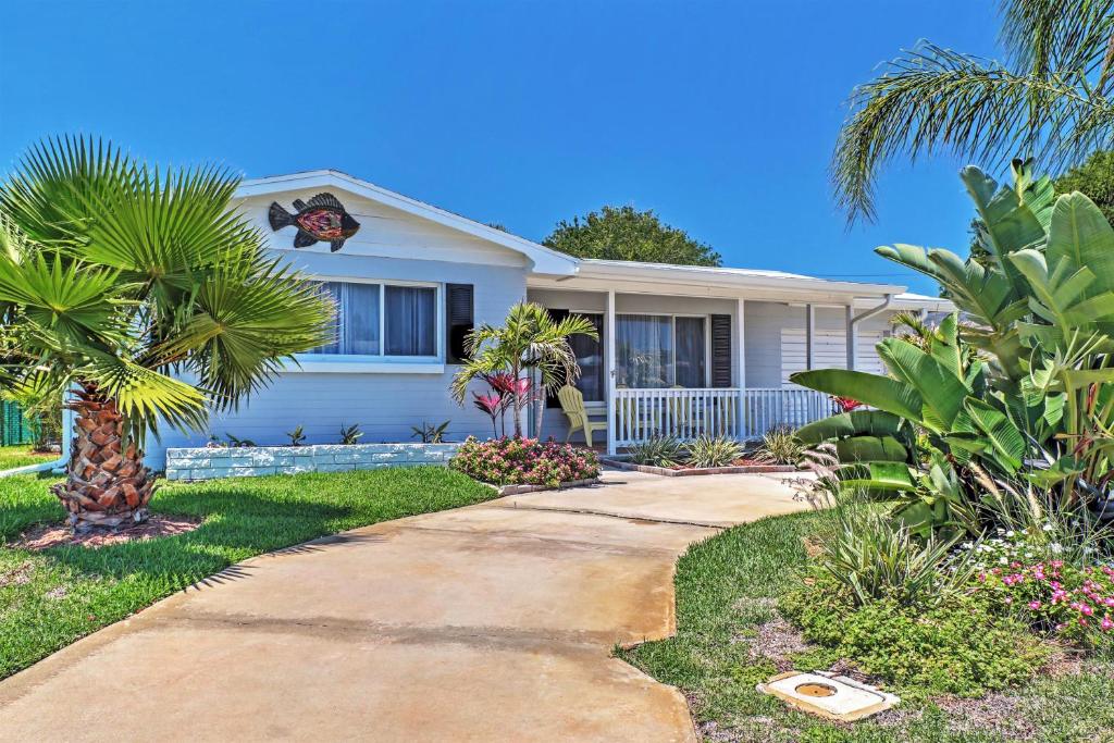 a white house with palm trees and a sidewalk at Ormond Beach Bungalow with Patio and Quiet Setting! in Ormond Beach
