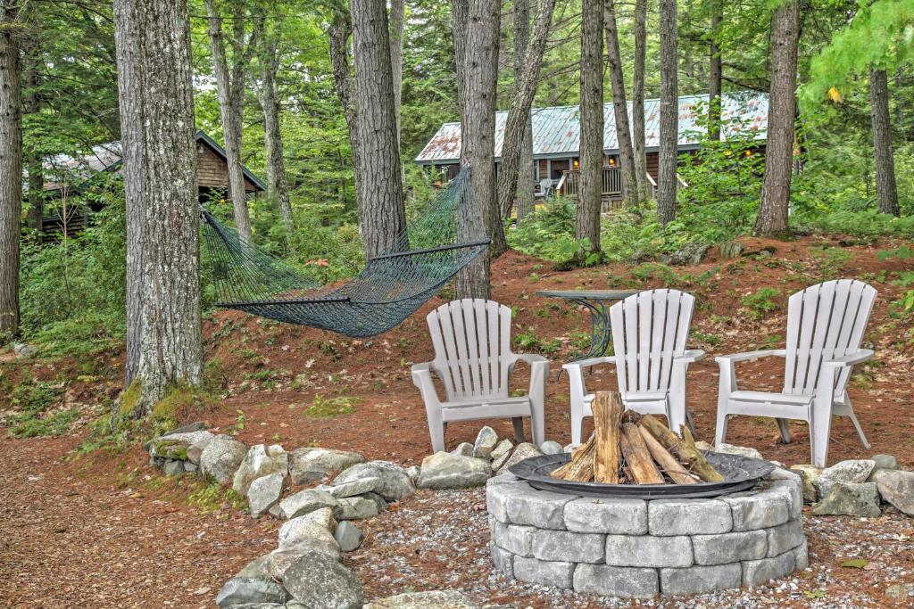 a fire pit with three chairs and a hammock in the woods at Waterfront Denmark Complex with Dock on 12 Acres! in Denmark