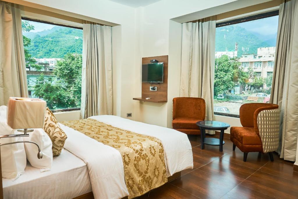 a hotel room with a bed and a large window at Ganpati Hotel Katra in Katra