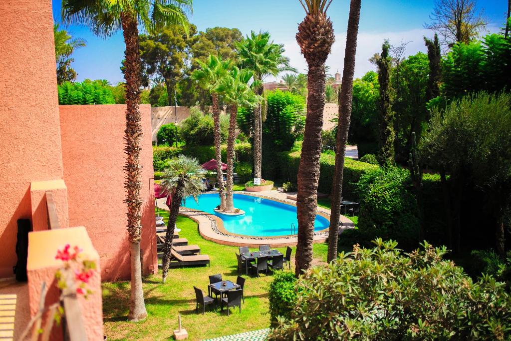 una vista sulla piscina in un cortile con palme di The Red House a Marrakech