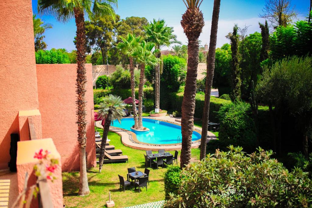 - une vue sur la piscine située dans une cour bordée de palmiers dans l'établissement The Red House, à Marrakech