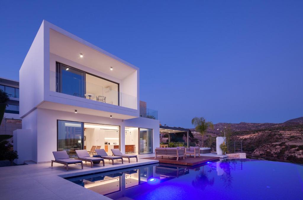 a modern house with a swimming pool at night at Thalassa in Paphos