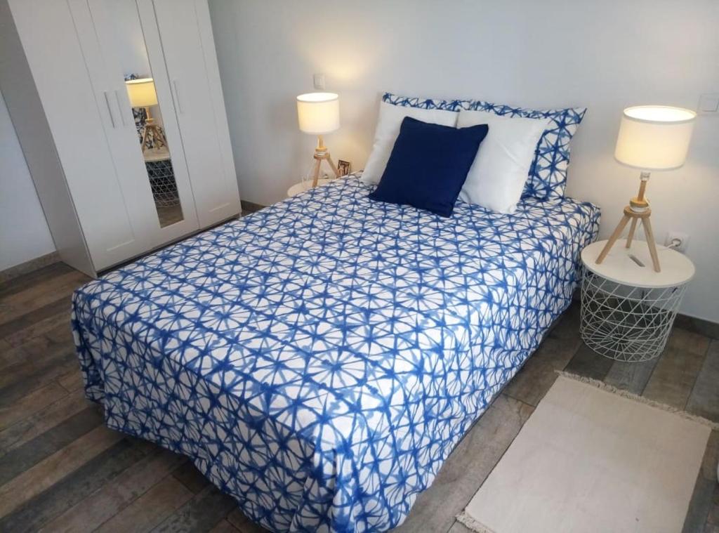a bedroom with a blue and white bed with two lamps at Piso a una parada de Atocha, amplio y luminoso in Madrid