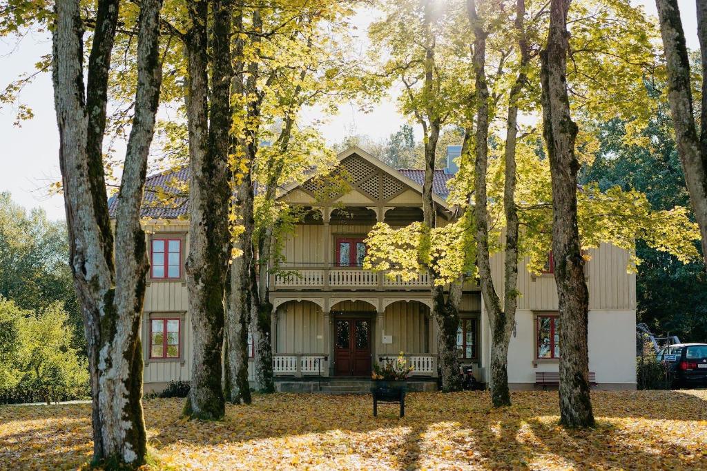 uma casa rodeada de árvores no outono em Lydde Gård em Kinna