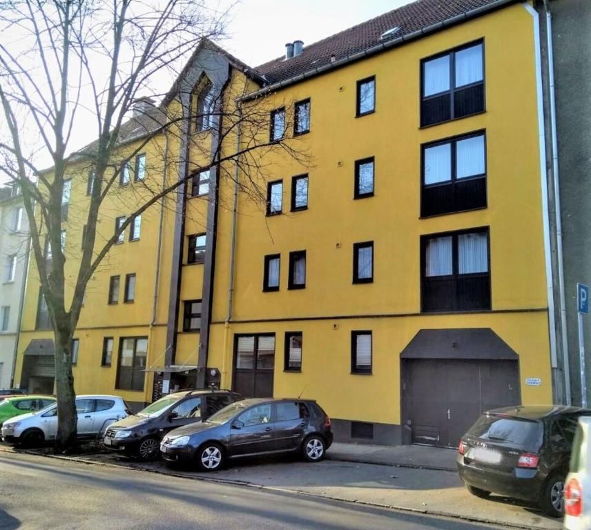 a yellow building with cars parked in front of it at Apparthaus Arosa in Essen