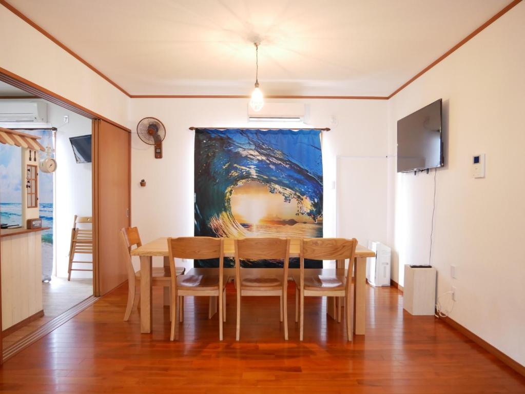 une salle à manger avec une table et un tableau mural dans l'établissement 子供部屋のある一棟貸切り 奄宿り Amayadori, à Amami