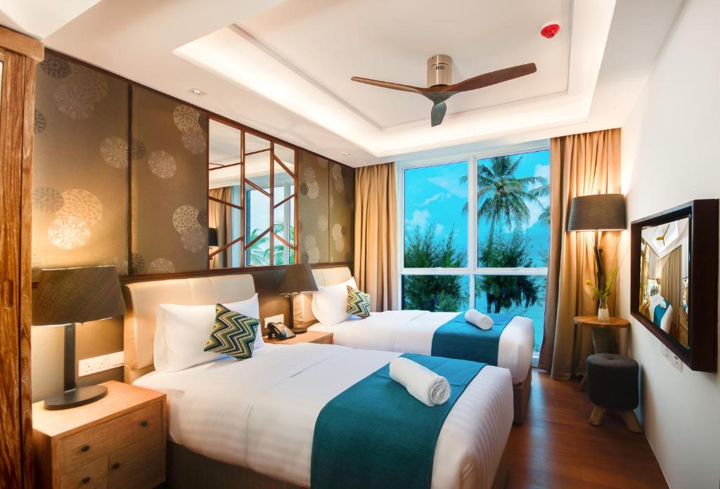 a hotel room with two beds and a window at Seasalter Maldives in Hulhumale