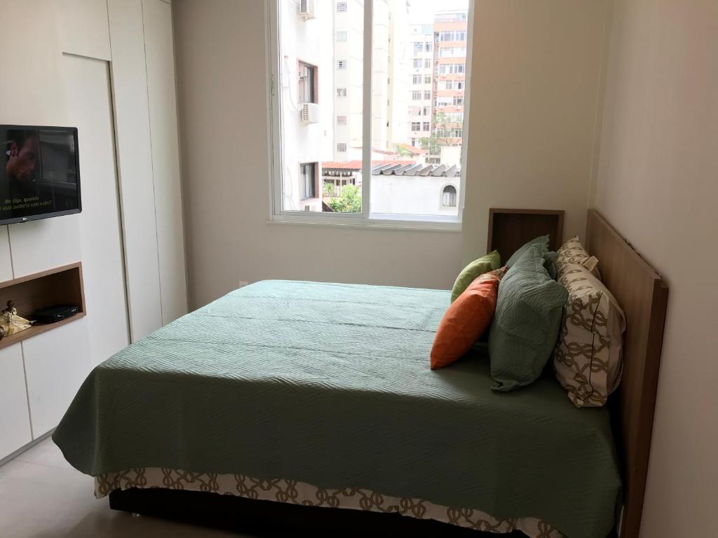 1 dormitorio con cama con almohadas y ventana en Fantástico STUDIO DIVISA COPACABANA IPANEMA REFORMADO E DECORADO en Río de Janeiro