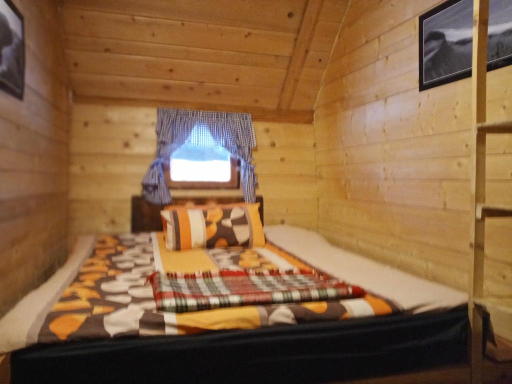 a bed in a log cabin with a window at Planinarski dom "Tornik" Zlatibor in Ribnica