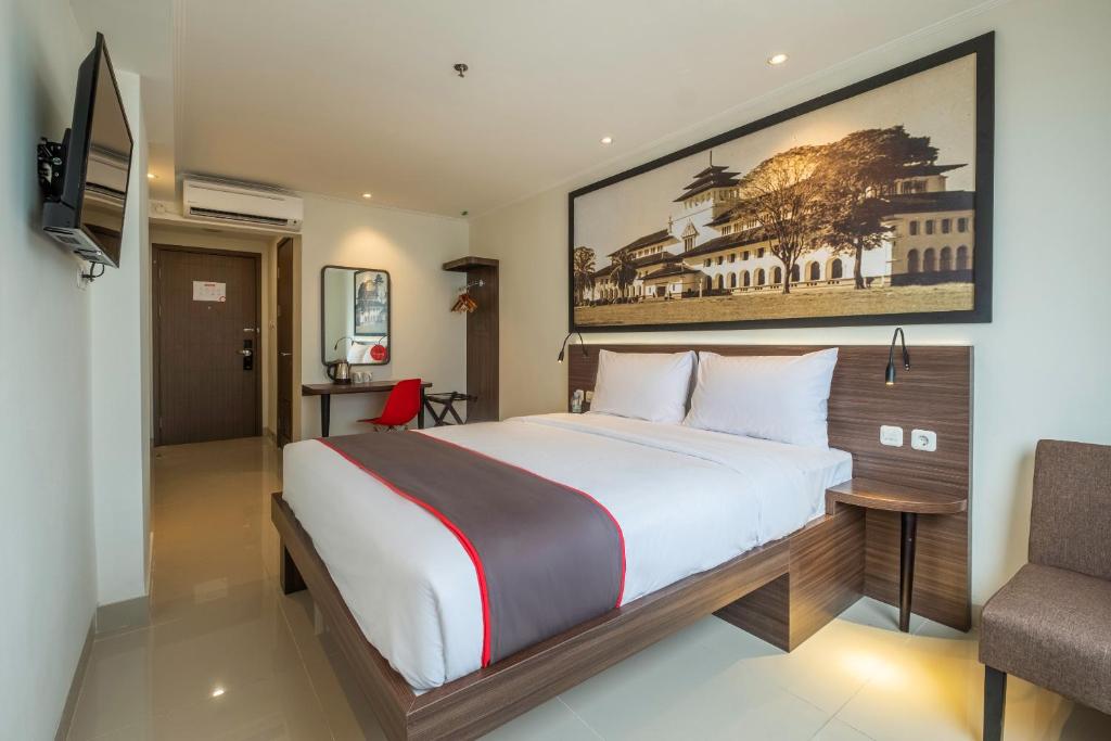 a bedroom with a large bed and a chair at SUPER OYO Collection O Hotel Pasar Baru Heritage in Bandung