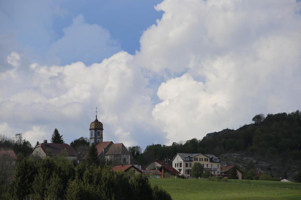 a group of houses in a field with a clock tower at le refuge des Marmottes in Saint-Laurent-du-Jura