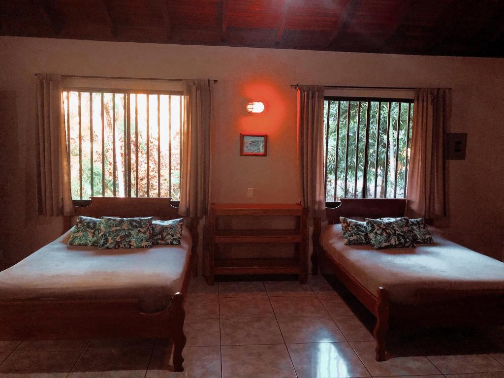 two beds in a room with two windows at Riviera Riverside Villas in Pavones