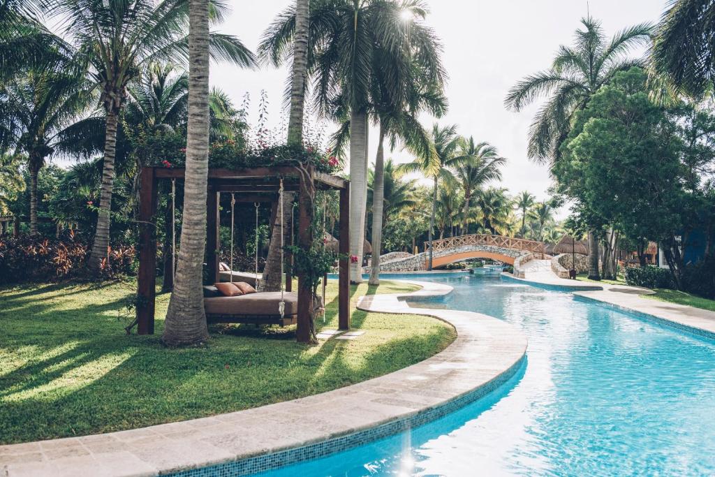 une piscine dans un complexe avec des palmiers et un pont dans l'établissement Iberostar Paraíso Beach, à Puerto Morelos