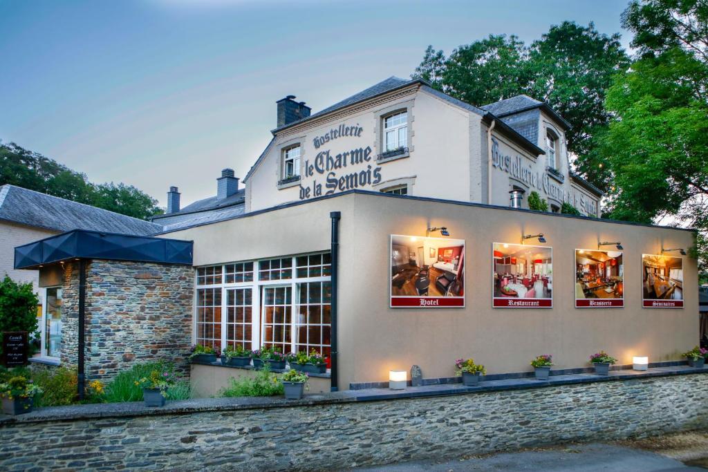 un magasin à l'avant d'un bâtiment avec des lumières dans les fenêtres dans l'établissement Hotel Le Charme de la Semois, à Alle