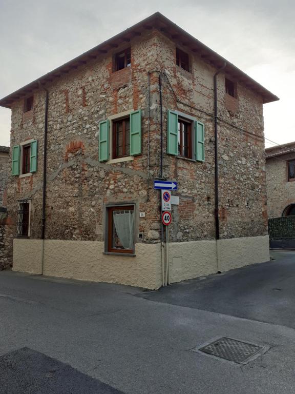 un edificio de ladrillo con ventanas verdes y un letrero de la calle en Casa Nostra Camaiore, en Camaiore
