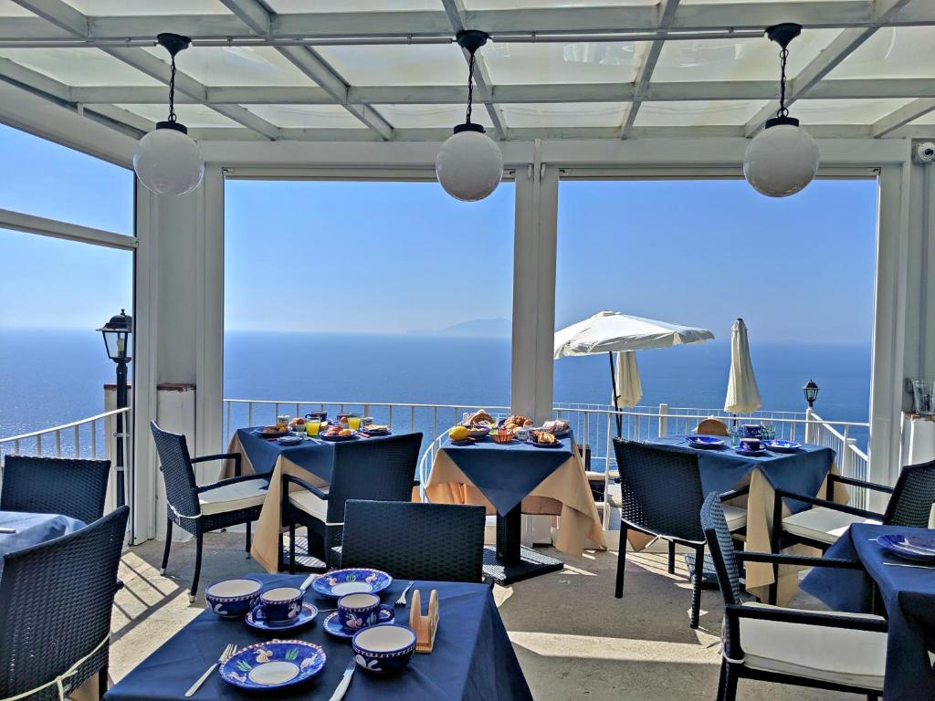 a balcony with tables and chairs and a view of the ocean at B&B Il Paradiso di Capri in Anacapri