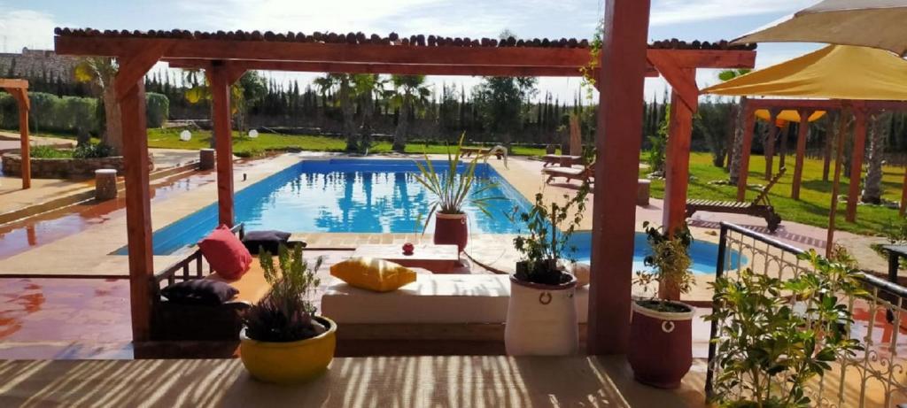 una piscina con piante in vaso e un pergolato di Terrasses vertes a Essaouira