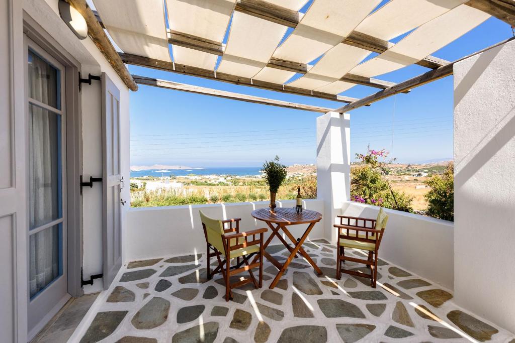 een patio met een tafel en stoelen op een balkon bij Agnanti Studios in Naousa