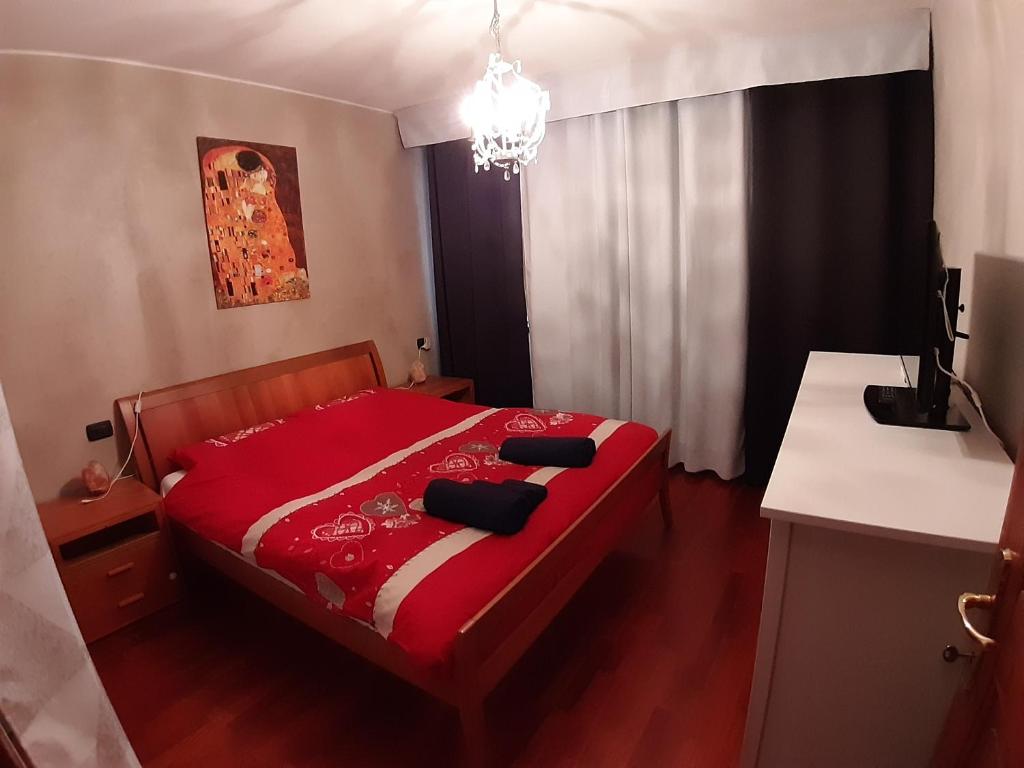 1 dormitorio con cama roja y lámpara de araña en Appartamento a Dimaro in Val di Sole, en Monclassico