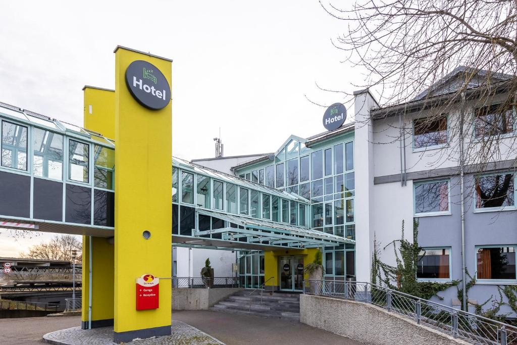 un edificio con una columna amarilla delante de él en Hotel Holledau, en Geisenhausen