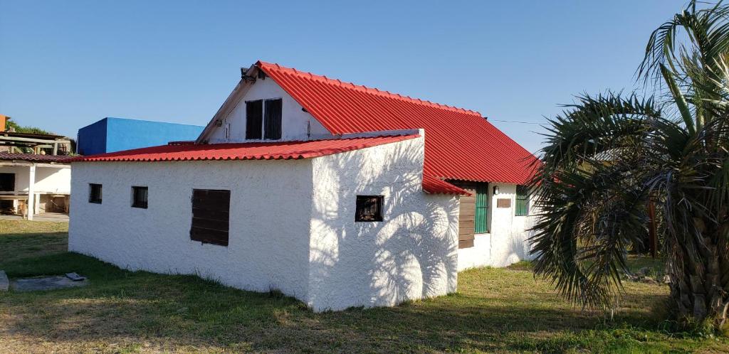 un edificio blanco con techo rojo junto a una palmera en Carpe Diem, en Aguas Dulces