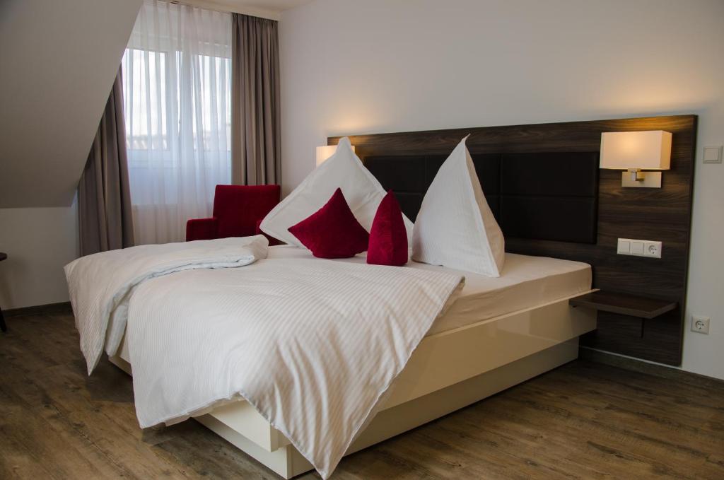 a bedroom with a large white bed with red pillows at Hotel Restaurant Lamm in Mönsheim
