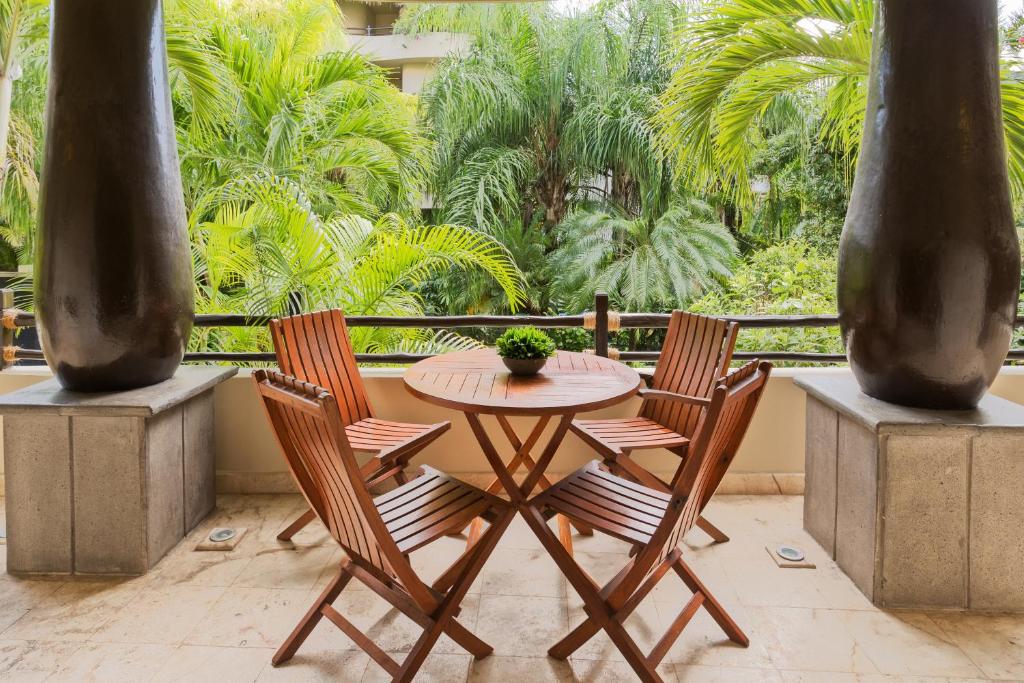 a patio with a table and chairs and palm trees at El Taj Oceanfront and Beachside Condo Hotel in Playa del Carmen