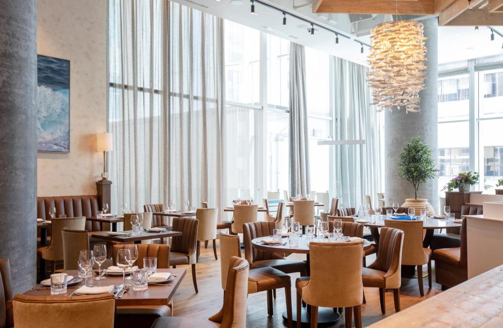a restaurant with tables and chairs and large windows at EXchange Hotel Vancouver in Vancouver