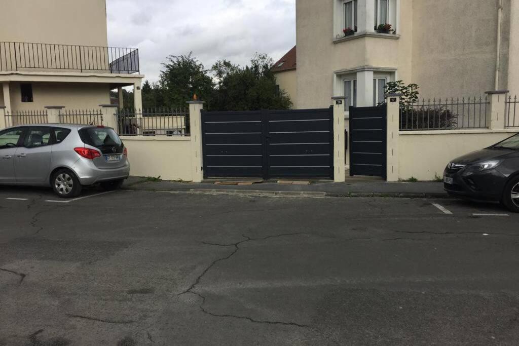 twee auto's geparkeerd op een parkeerplaats voor een hek bij F3 agréable et calme in Château-Thierry