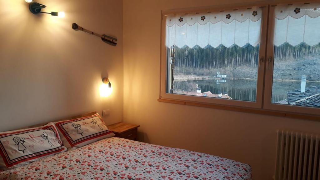 een slaapkamer met een bed en een groot raam bij B&B Cuore Trentino in Baselga di Pinè
