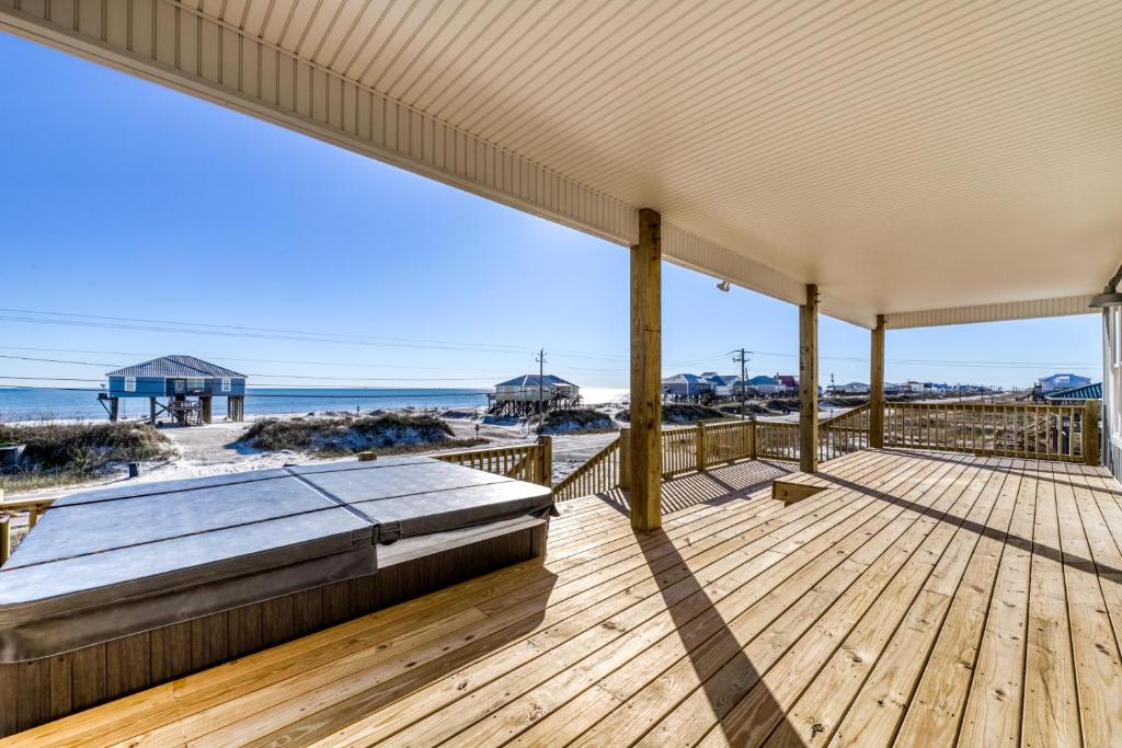 a wooden deck with a bed and the beach at Picture Perfect in Dauphin Island