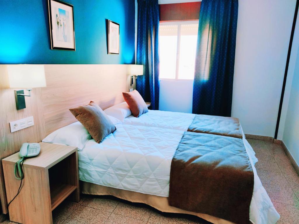 a bedroom with a bed and a table with a phone at Hotel Catalán Puerto Real in Puerto Real