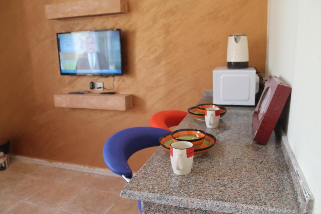 a table with two chairs and a tv on a wall at Relax House For Studio Rooms Apartment in Aqaba