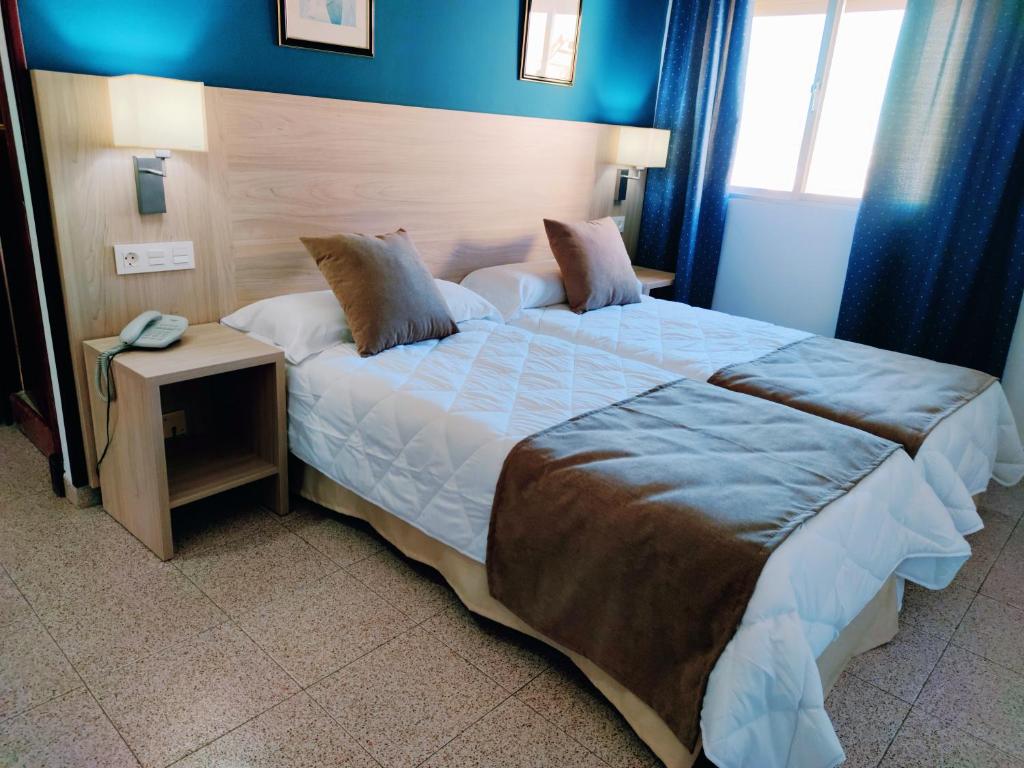 a bedroom with a large bed with a phone on it at Hotel Catalán Puerto Real in Puerto Real