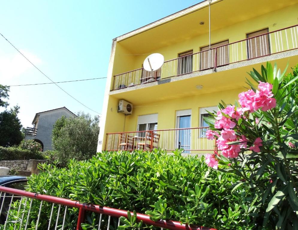 un edificio amarillo con flores rosas delante de él en Apartments Zrinko, en Novi Vinodolski