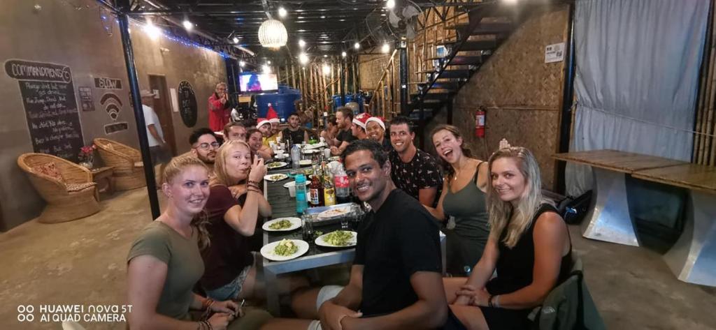a group of people sitting at a table with food at Big Paul Hostel in El Nido