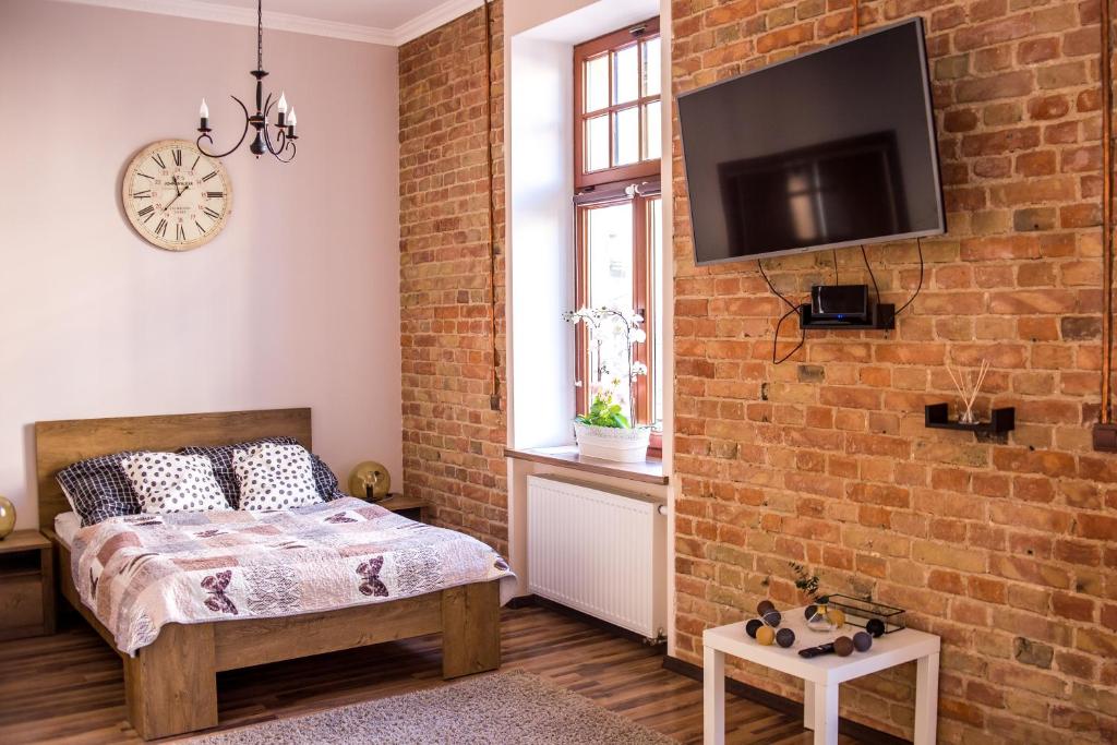 1 dormitorio con cama y pared de ladrillo en Voal Apartamenty, en Lublin