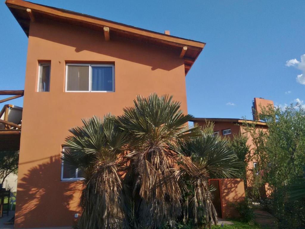 a house with palm trees in front of it at Cabaña Las hermanas in Capilla del Monte