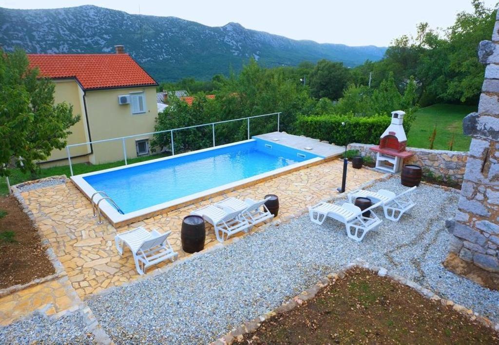 Grižane的住宿－Villa Kate - cosy place in the nature，一个带2把躺椅的游泳池以及1栋房子