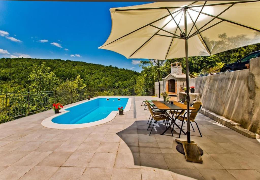 patio con tavolo, ombrellone e piscina di Villa Brapa - open swimming pool a Hrvace