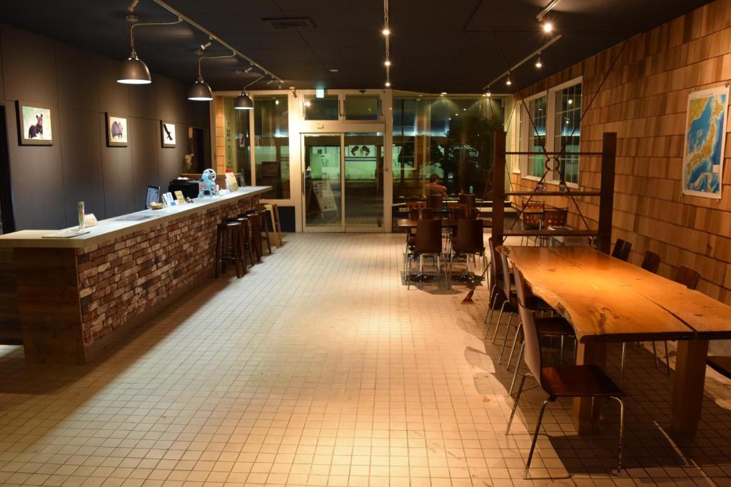 een restaurant met houten tafels en een bar bij Noboribetsu Guest House AKA & AO in Noboribetsu