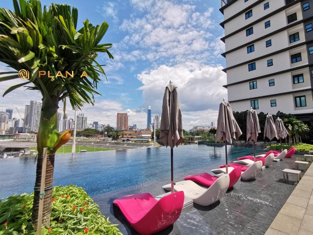 a pool with chairs and umbrellas next to a building at Opus LIV Signature in Kuala Lumpur