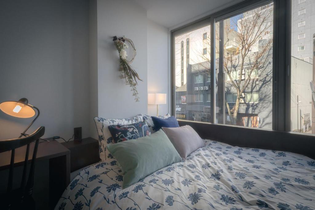 um quarto com uma cama com almofadas e uma janela em Hotel Trim em Kanazawa