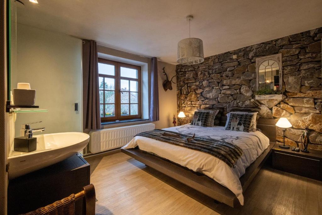 a bedroom with a stone wall and a bed and a sink at Ardennes Woods in Marche-en-Famenne