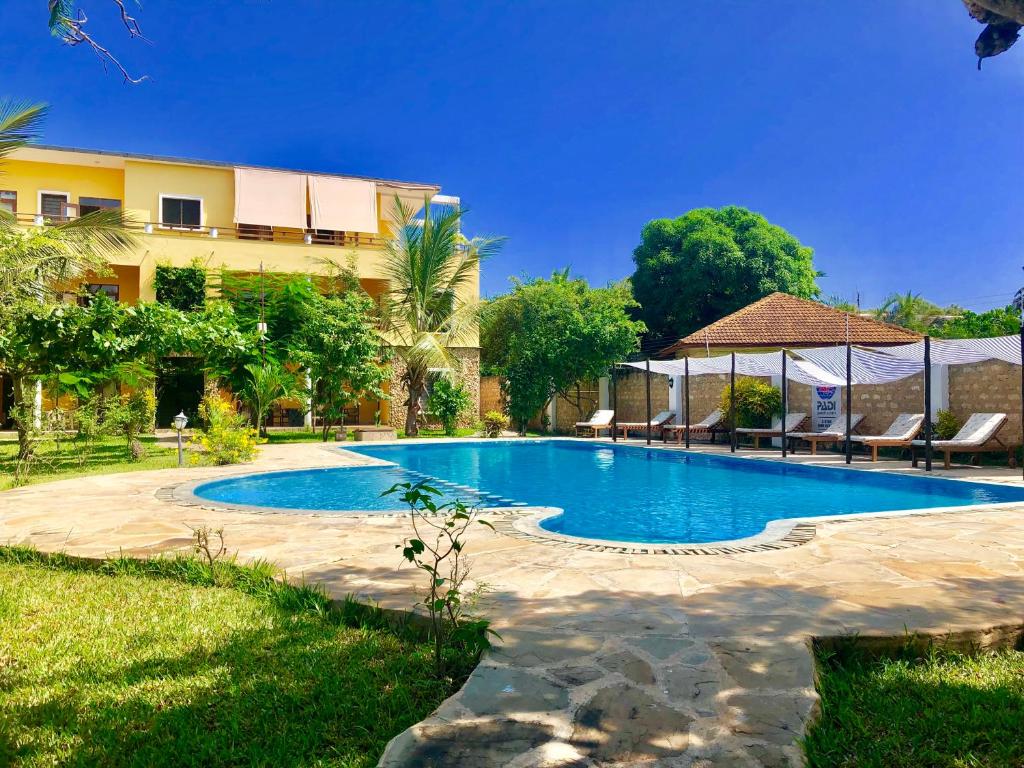 une piscine devant un immeuble dans l'établissement Flametree Beach Homes, à Diani Beach