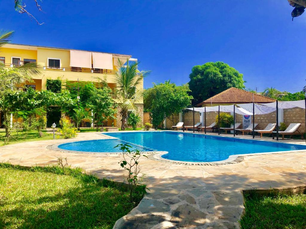 a swimming pool in front of a building at Flametree Beach Homes in Diani Beach