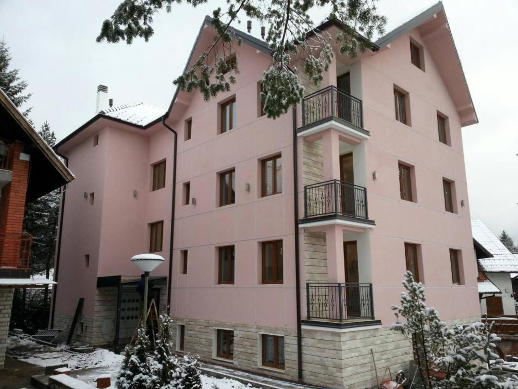 a pink building with snow on the ground at Vila Meridijan in Zlatibor