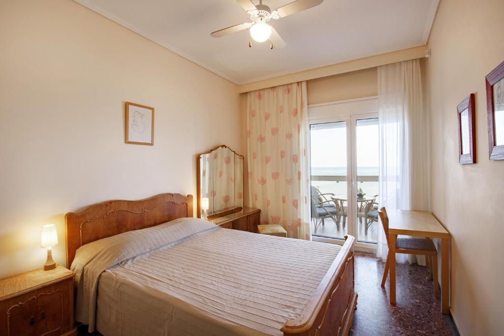a bedroom with a bed and a window and a table at Metaxa Seafront Apartment in Perea